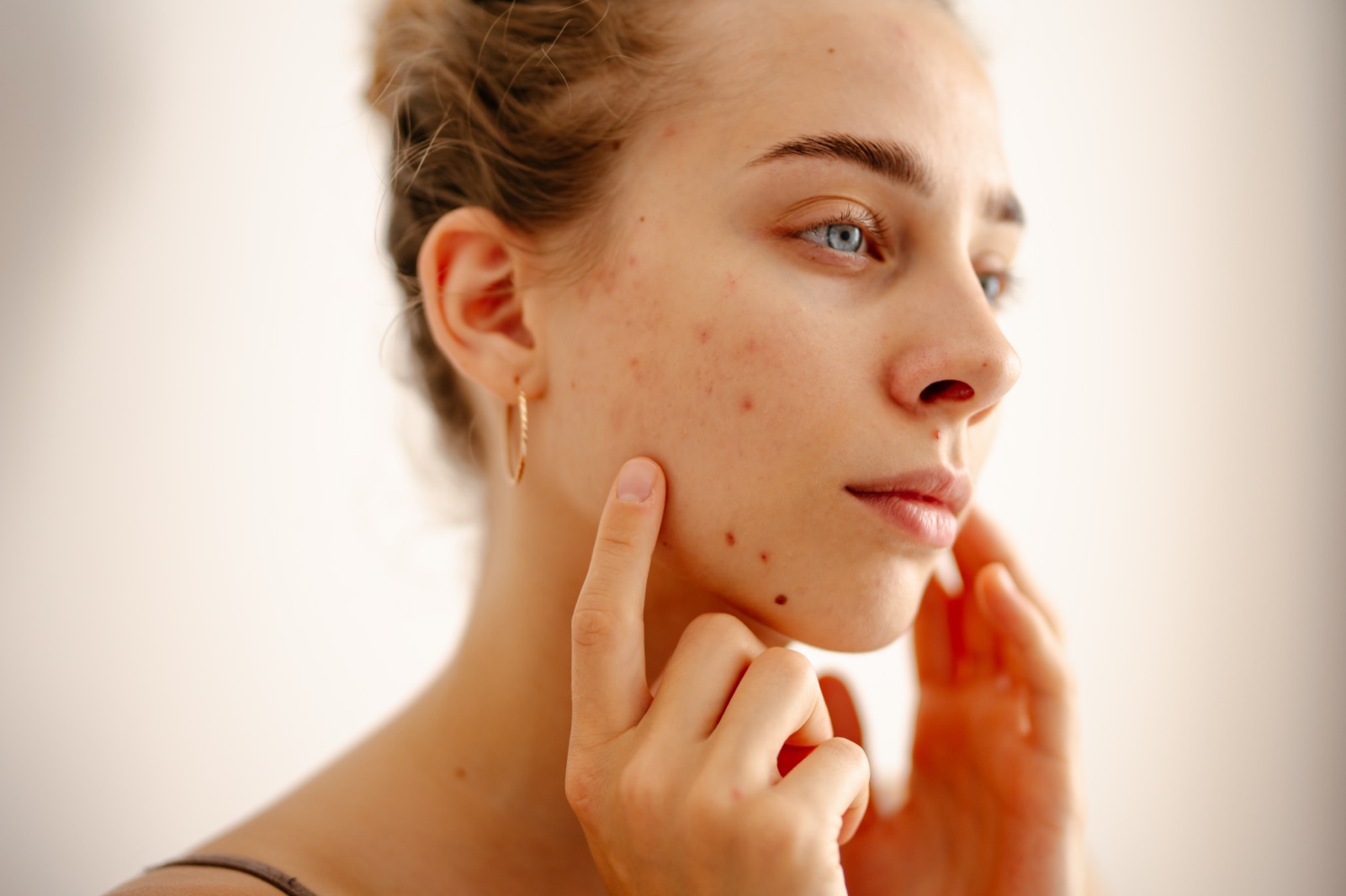 Young woman examining her skin in natural light